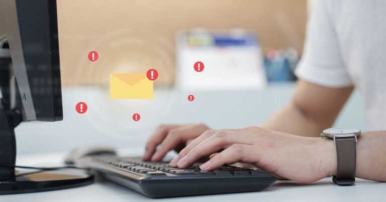 Typing on a keyboard with an email icon hovering above the keyboard to represent phishing vulnerabilities.