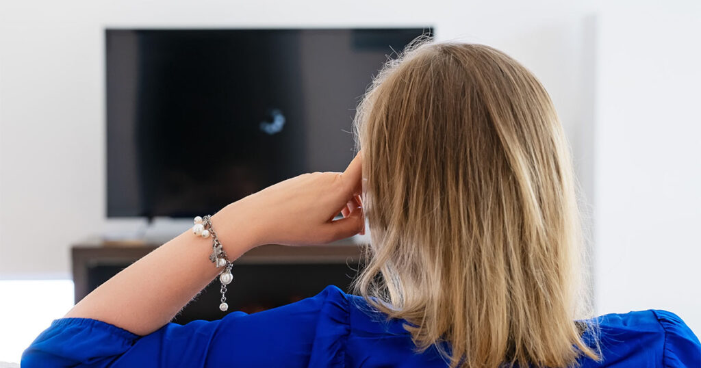 Back of woman's head attempting to watch TV but the home internet is interrupting streaming.